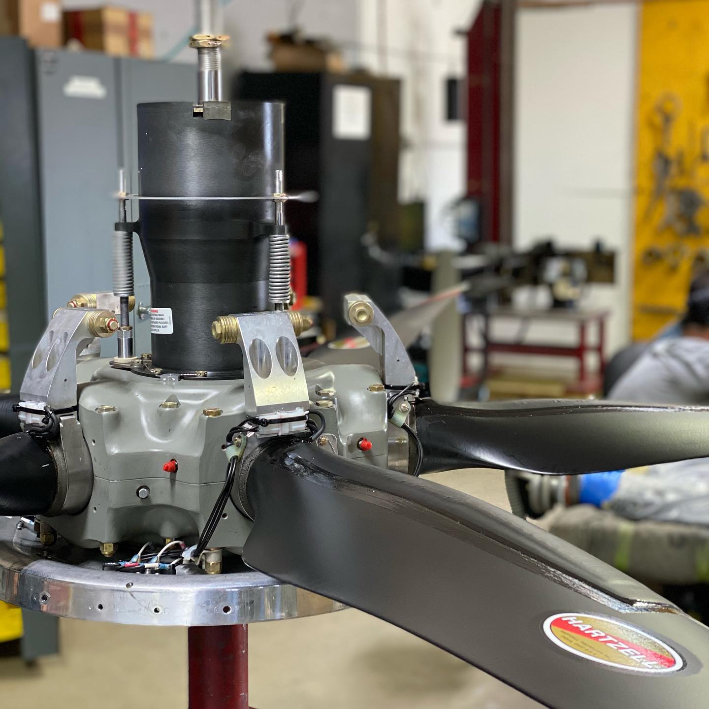 A technician is repairing a propeller in a well-equipped workshop, surrounded by tools and machinery.