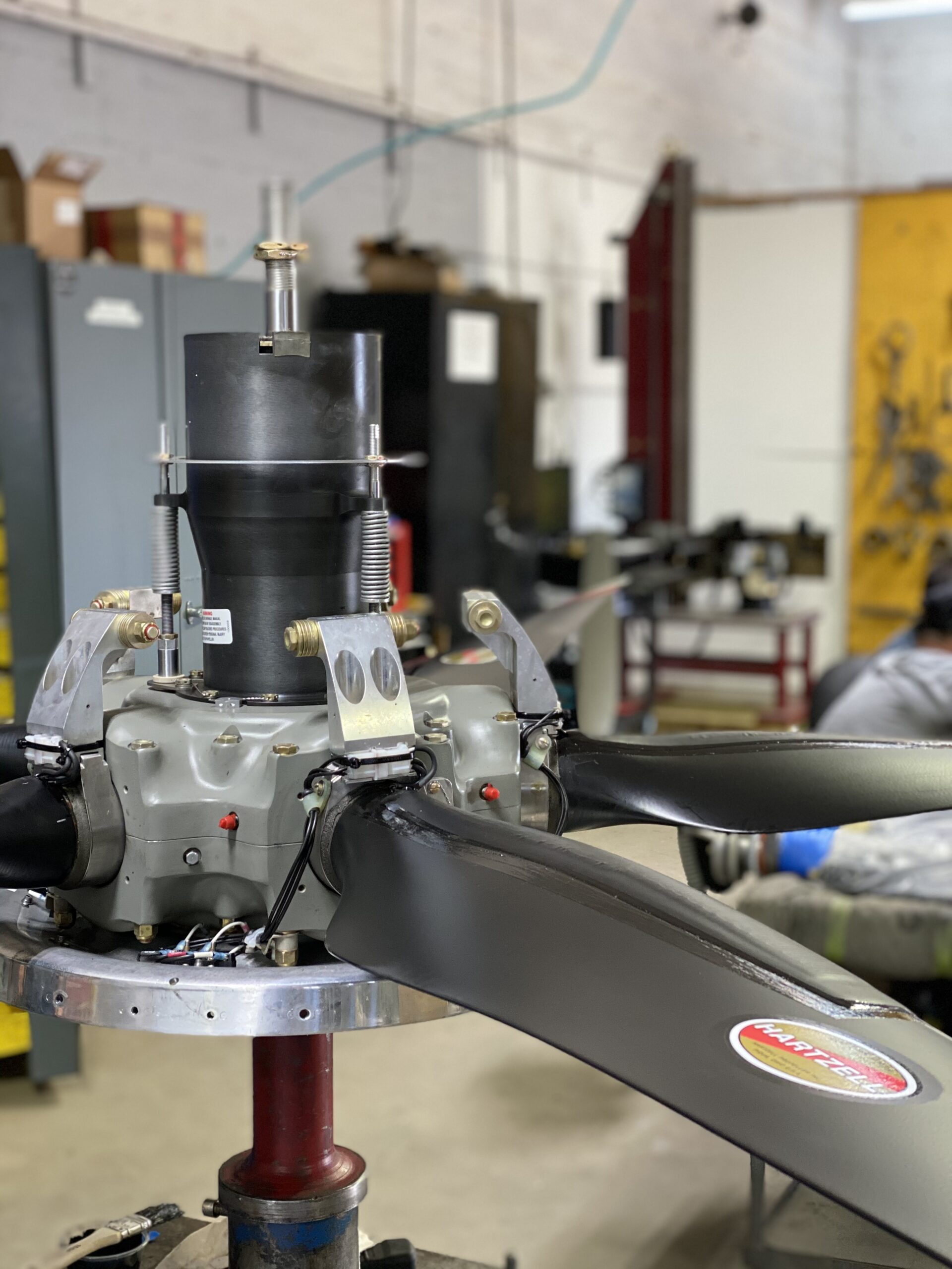 A technician is repairing a propeller in a well-equipped workshop, surrounded by tools and machinery.